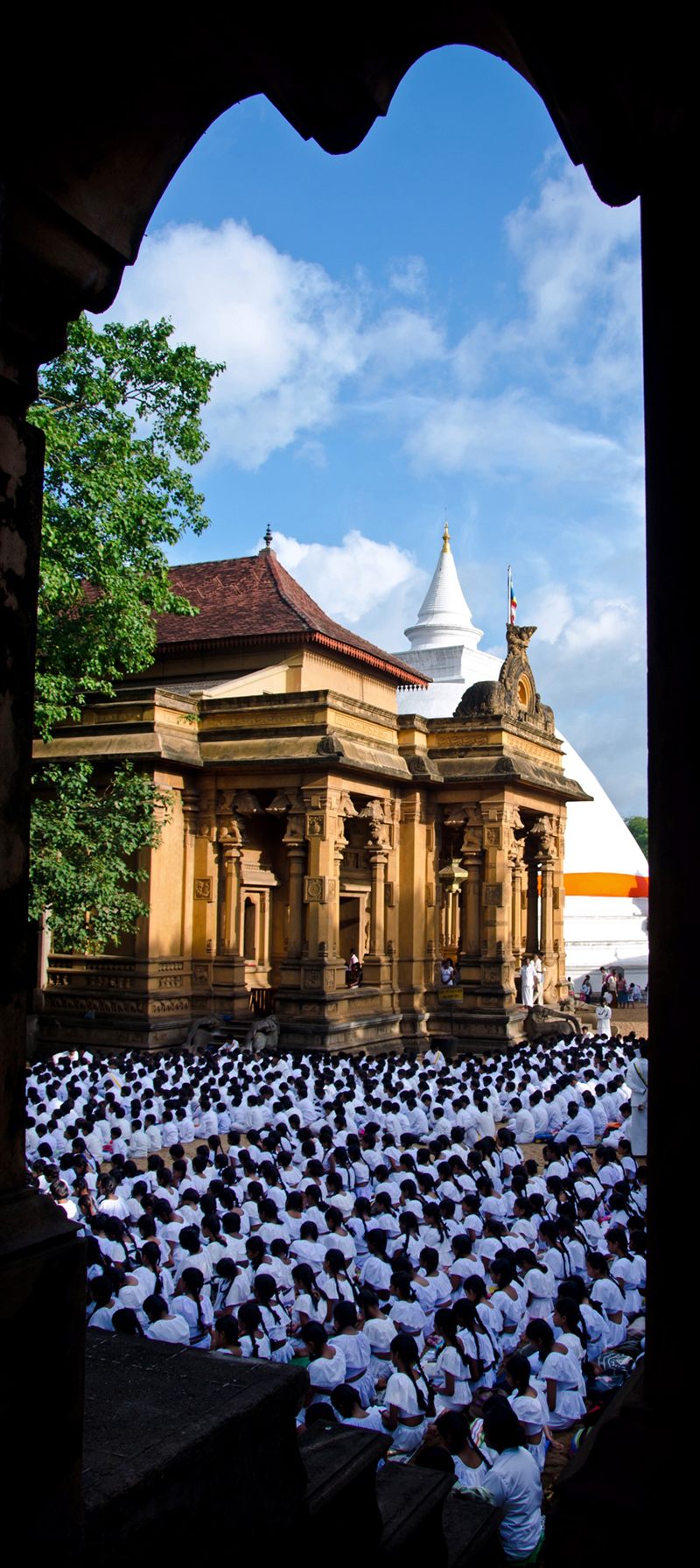 White-clad worshippers gathered beneath a temple in Sri Lanka, by Rajiv CG